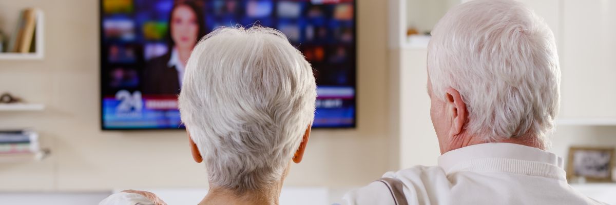 Elderly couple wearing hearing aids and watching tv