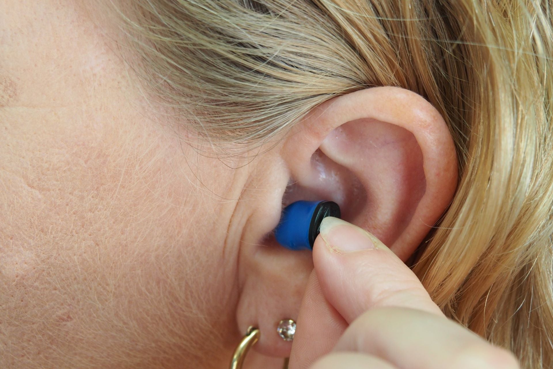 a woman putting an in the ear hearing aid