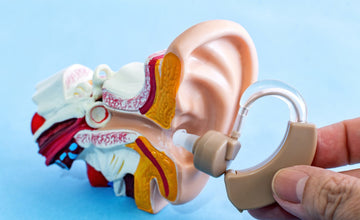 doctor holding a hearing aid to a model ear