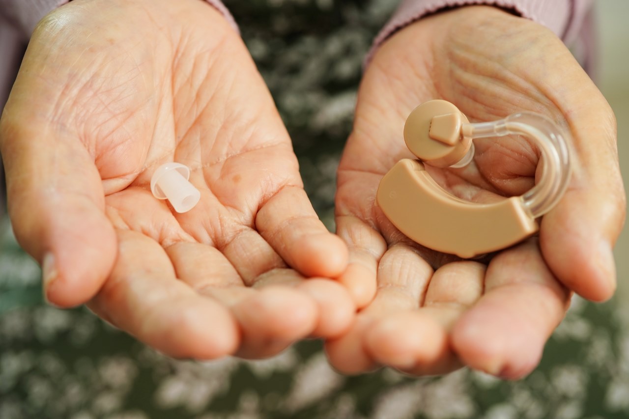 senior woman holding hearing aids on both of her hands