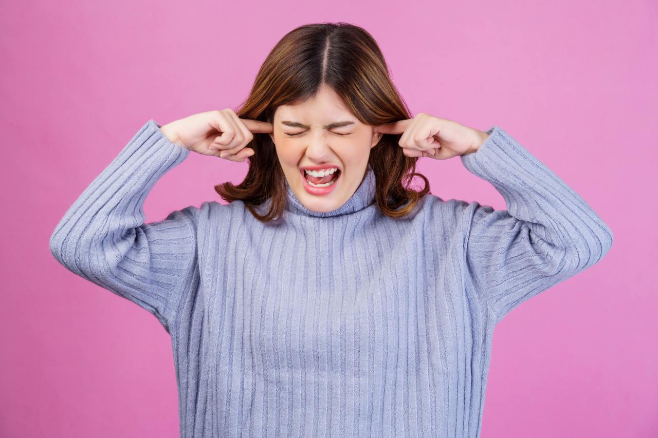 annoyed woman with both her fingers stuck to her ears